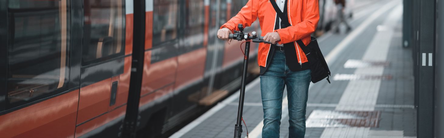 Man with electric scooter by train