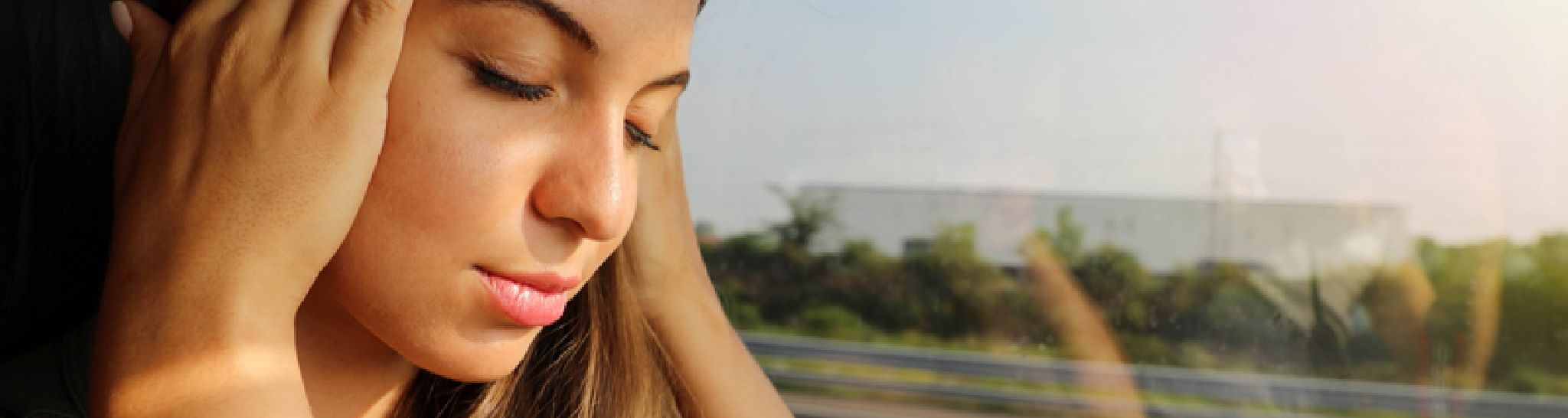 woman holding her head in a train