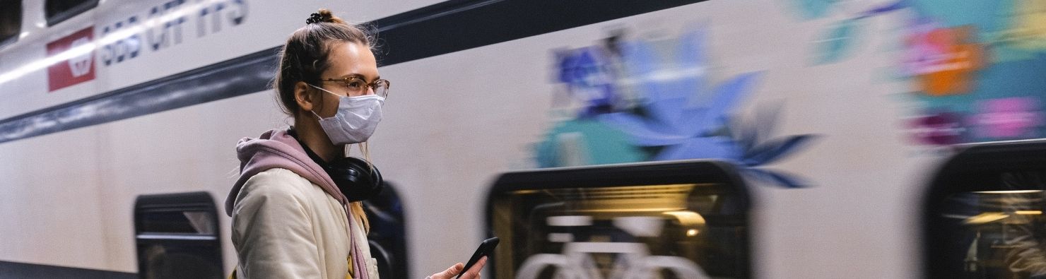 Travelling in a pandemic by train woman in a mask by a train