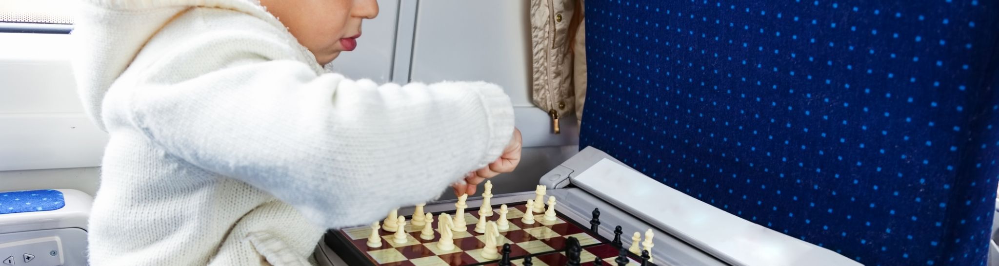 fun travel ideas with children child playing chess on the train - ideas for fun journeys with children